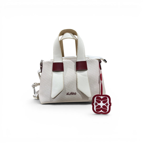 COC Store Aldino textured top handle bag in off-white fabric with white and burgundy faux leather accents and a decorative charm.